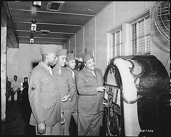 First of the famous Mills Brothers quartet to enter Army service, Pvt. Harry Mills stops at the jukebox in the Reception Center PX